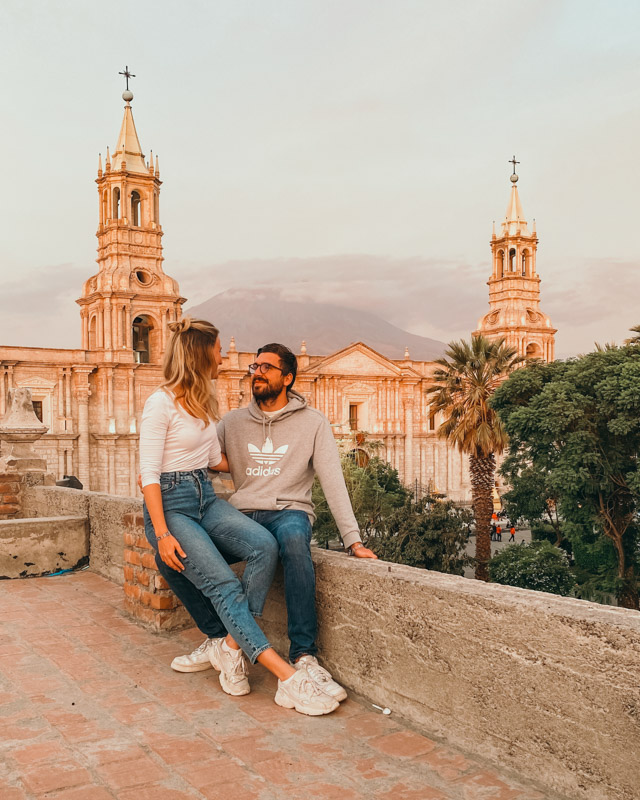 A couple is sitting on a terrace, overlooking the cathedral and the main square in Arequipa, Peru