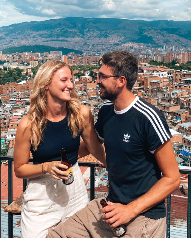 A couple sitting in front of the skyline of Medellin in Comuna 13, Colombia