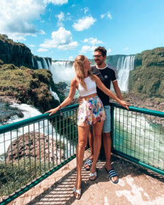 A couple stands in front of Iguazu Falls between Brazil and Argentina