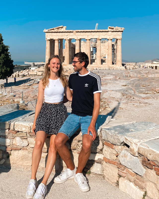 Couple sits in front of Acropolis in Athens, Greece