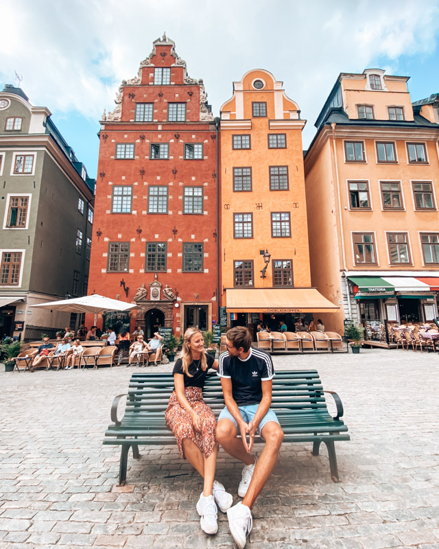 A couple sits on a bench in front of the famous houses in Gamla Stan, Stockholm, Sweden