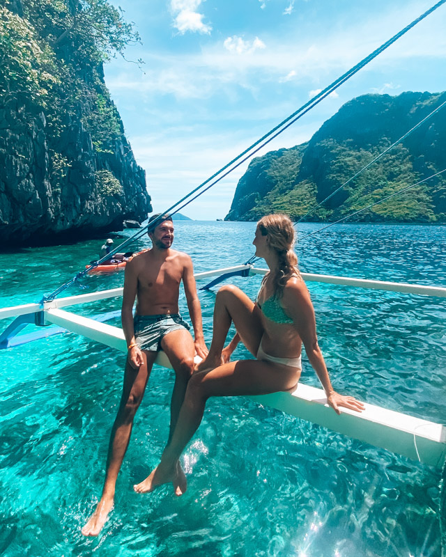 Couple sits on the edge of a boat in El Nido, Philippines