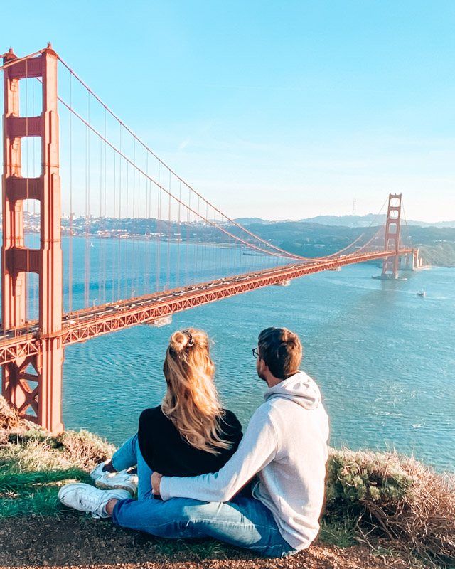 A couple sits in front of the Golden Gate Bridge in San Francisco on a roadtrip through California, USA