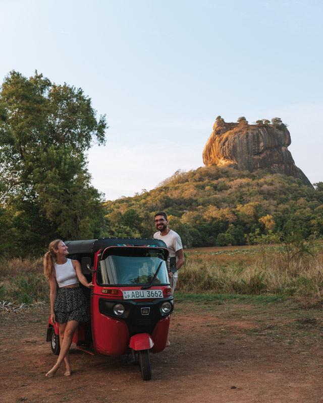 Tuktuk rental Sri Lanka - a couple stands on its rented tuktuk in front of Sigiriya rock